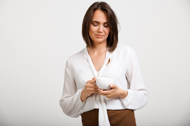 思いやりのある動揺のファッション女性がコーヒーを飲む、思考