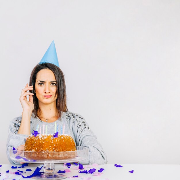 Thoughtful woman behind birthday cake