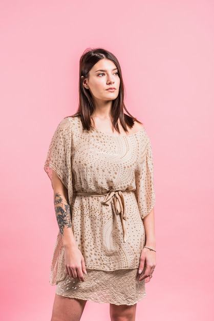 Thoughtful woman in dress on pink background