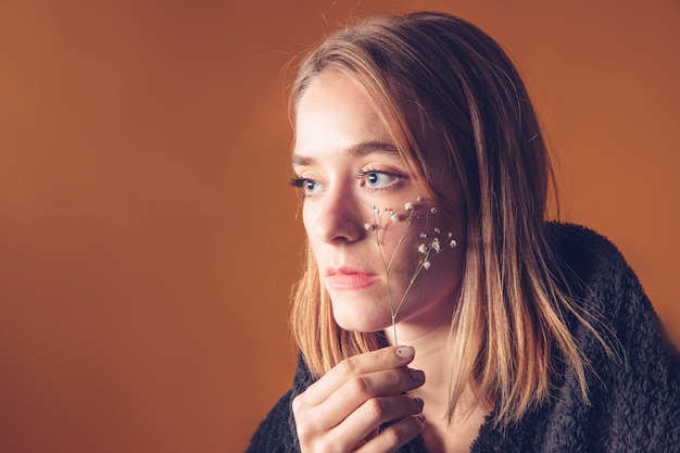 Free photo thoughtful woman holding flower at face