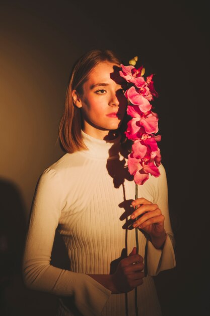 Thoughtful woman holding pink flower 