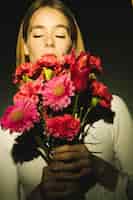 Free photo thoughtful woman holding pink flowers bouquet