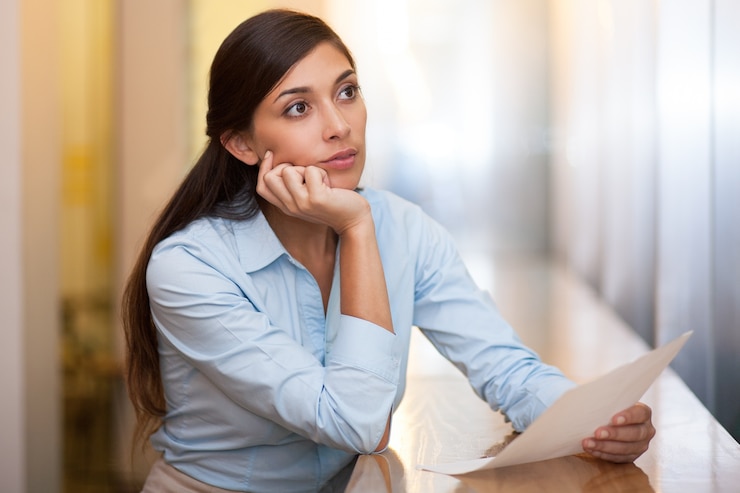 Free Photo thoughtful woman holding sheet of paper in cafe