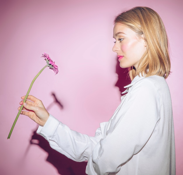 Free photo thoughtful woman looking at gerbera flower