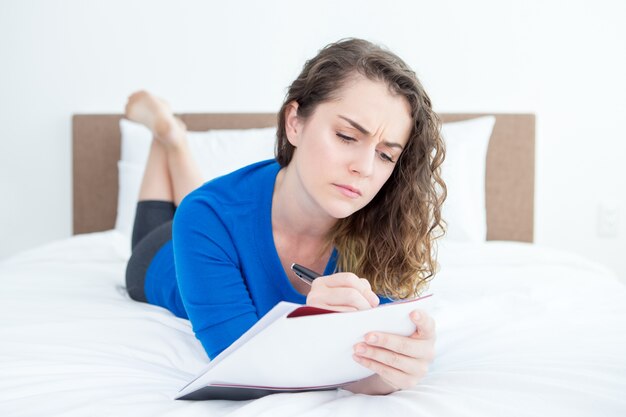 Thoughtful Woman Lying on Bed and Writing