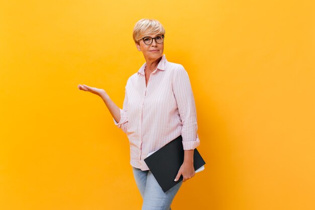 Thoughtful woman in pink shirt and eyeglasses poses with documents