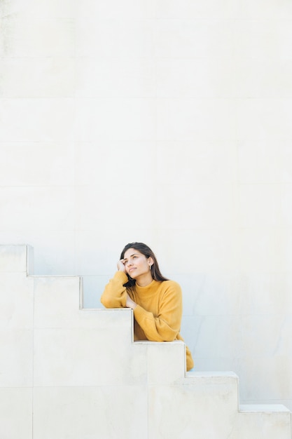 thoughtful woman standing against white wall