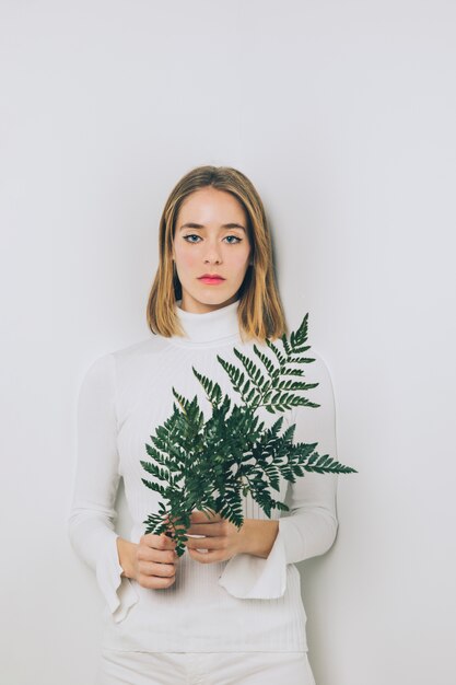 Thoughtful woman standing with fern leaves 