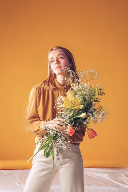 Thoughtful woman standing with flowers bouquet 