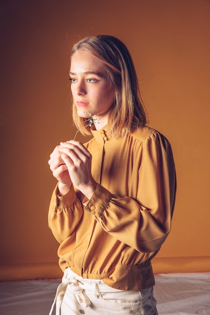 Thoughtful woman standing with small flower