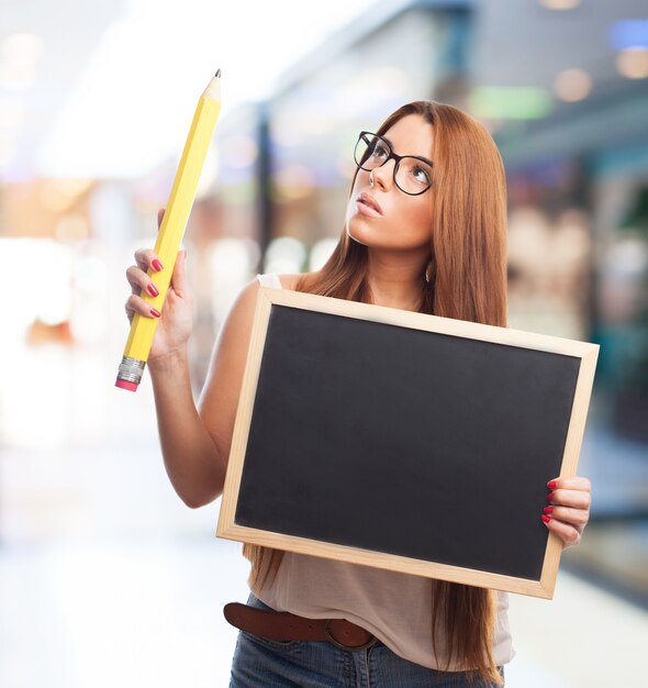 Thoughtful woman with blackboard and pencil