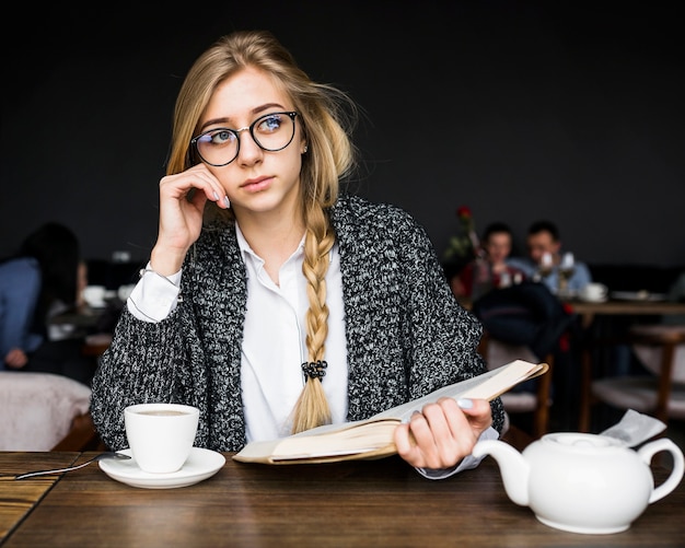 カフェでの本を持つ思いやりのある女性