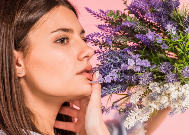 Thoughtful woman with bright flowers bouquet 