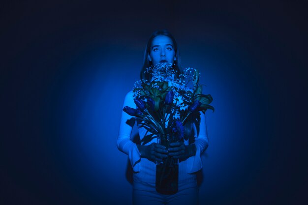 Thoughtful woman with flowers in glass vase 