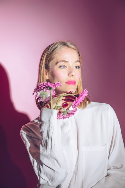 Thoughtful woman with gerbera flowers in shirt sleeve