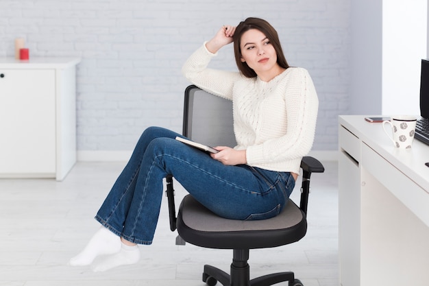 Thoughtful woman with notepad in office