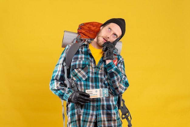 thoughtful young backpacker with black hat holding airplane ticket