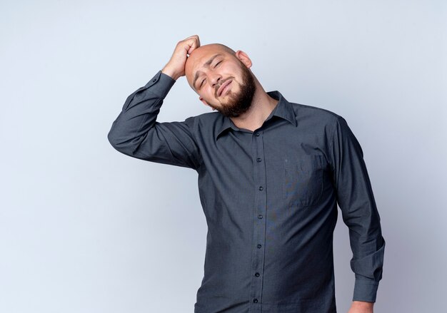 Thoughtful young bald call center man putting hand on head looking at front isolated on white wall