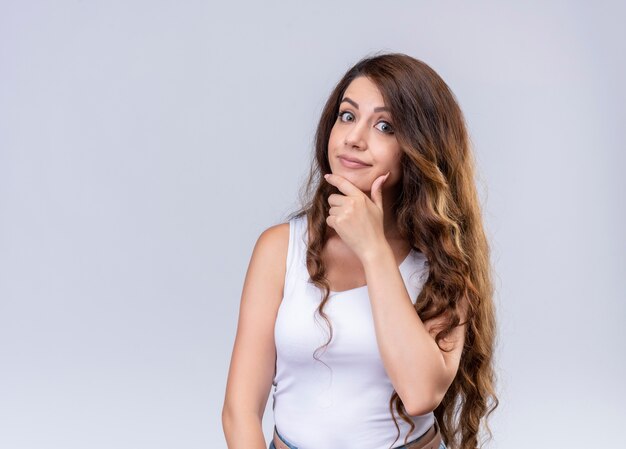 Thoughtful young beautiful girl putting hand on chin on isolated white wall with copy space