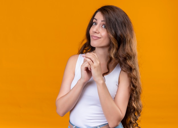 Thoughtful young beautiful girl putting hands together on isolated orange wall with copy space