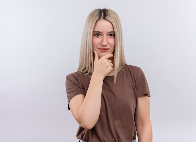 Thoughtful young blonde girl putting hand on chin on isolated white wall with copy space
