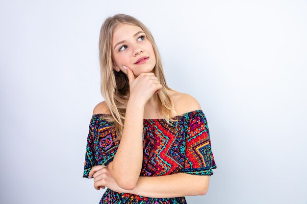 Thoughtful young blonde slavic woman putting hand on her chin and looking at side 