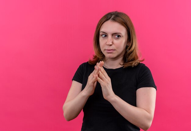 Thoughtful young casual woman putting hands together on isolated pink wall with copy space