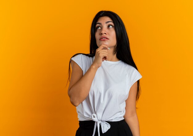 Thoughtful young caucasian woman holds chin looking up