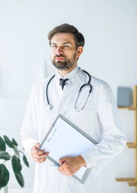 Thoughtful young doctor with clipboard