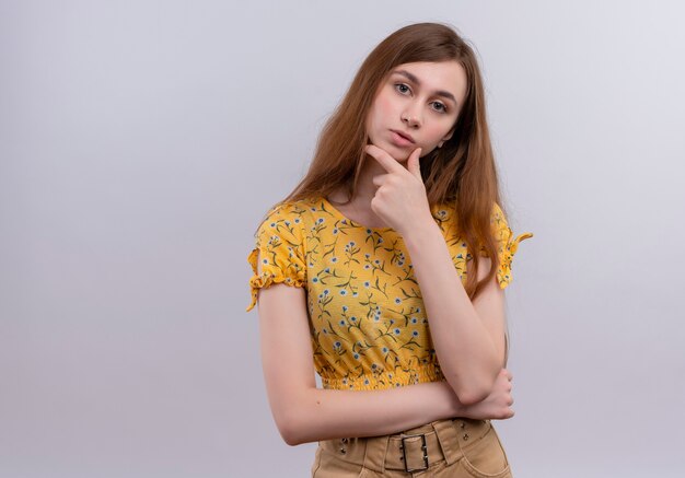 Thoughtful young girl putting hand on chin on isolated white wall with copy space