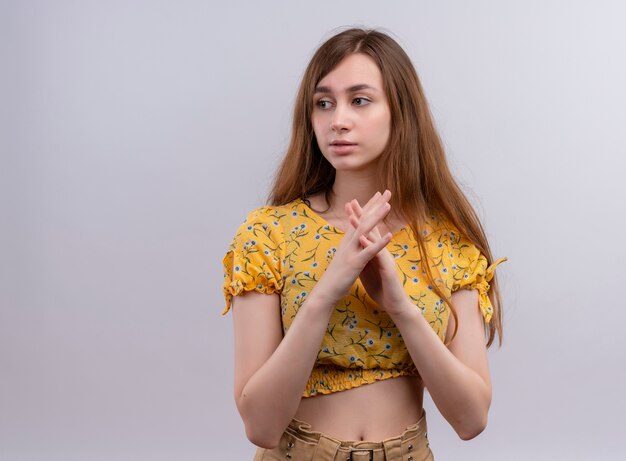 Thoughtful young girl putting hands together and looking at left side on isolated white wall with copy space