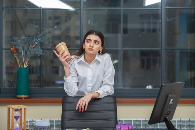 Thoughtful young lady holding coffee cup and thinking