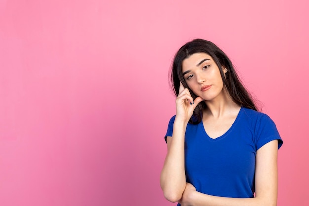 Thoughtful young lady holding her hand to her head and looking at the camera High quality photo