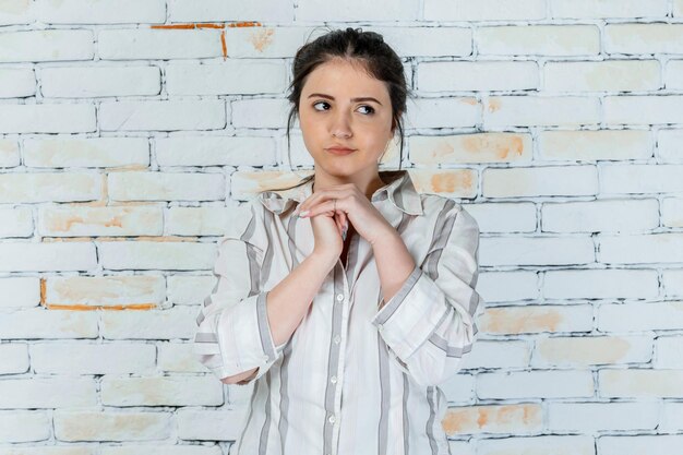 Thoughtful young lady keeps hands together and looks aside High quality photo