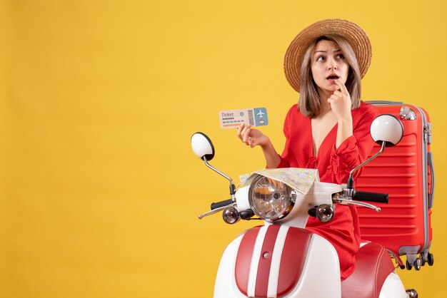 thoughtful young lady in red dress holding ticket on moped