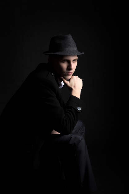 Thoughtful young man in hat in the dark