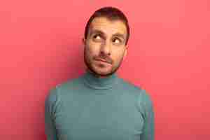 Free photo thoughtful young man looking at side isolated on pink wall