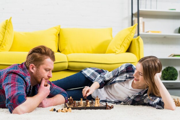 Thoughtful young man looking at smiling woman playing the chess game