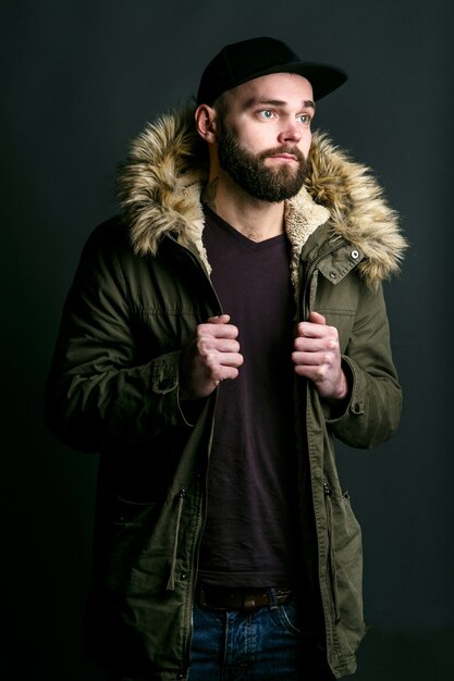 Thoughtful young man in parka with fur hood 