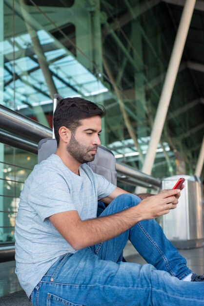 床に座って、電話を見て思いやりのある若い男