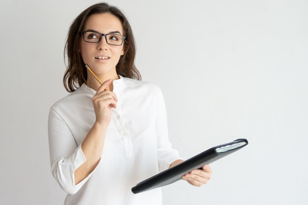 Thoughtful young pretty woman holding file and pencil