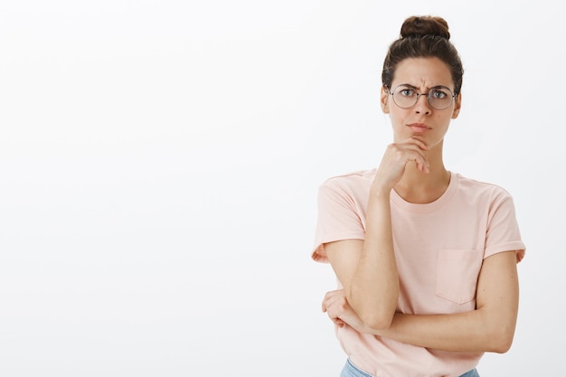 Foto gratuita riflessivo giovane donna alla moda in posa contro il muro bianco