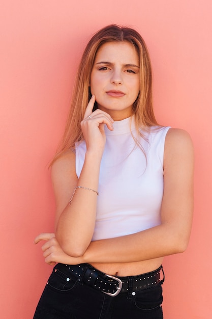 Free photo thoughtful young woman against peach backdrop