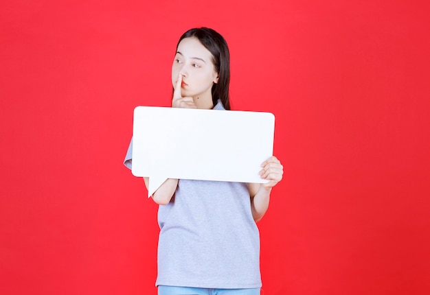 Thoughtful young woman holding board and looking away