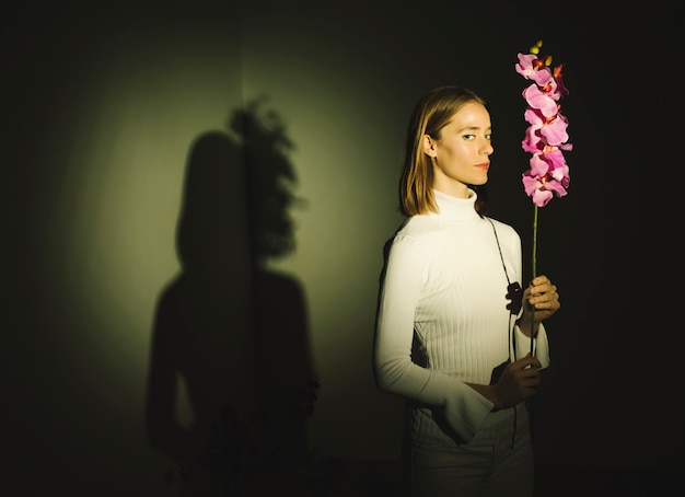 Free photo thoughtful young woman holding bright flower