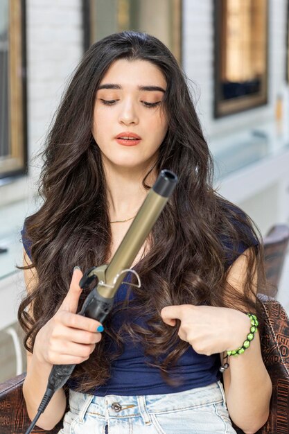 Thoughtful young woman holding hair dryer and looking at it High quality photo