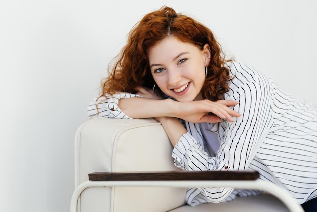 Thoughtful young woman staring intently ahead at the camera relaxes on a sofa at home