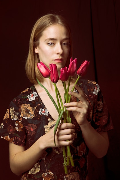 Free photo thoughtful young woman with red tulips