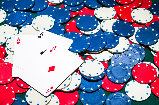 three aces card over the white; blue and red casino chips