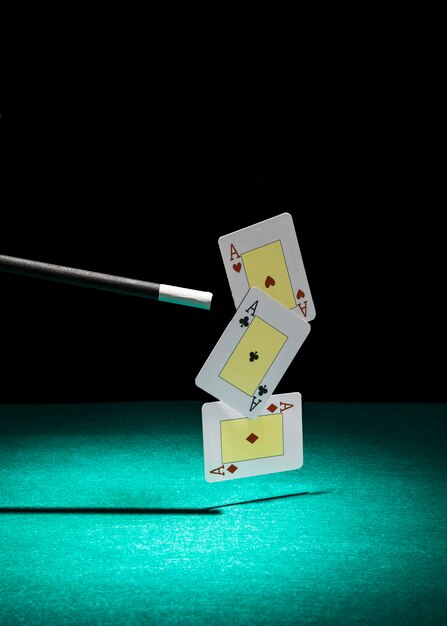 Три туза игральной карты в воздухе с волшебной палочкой на зеленом фоне